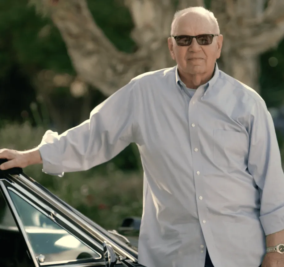 Frank wearing sunglasses and standing by a car